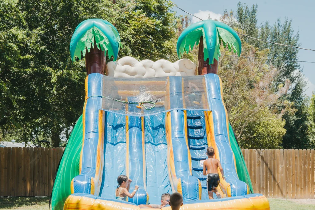 ילדים משחקים במגלשת מים מתנפחת בחצר